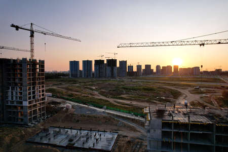 Tower crane on construction site on sunset background. Arial view of the cranes the conctruct the...