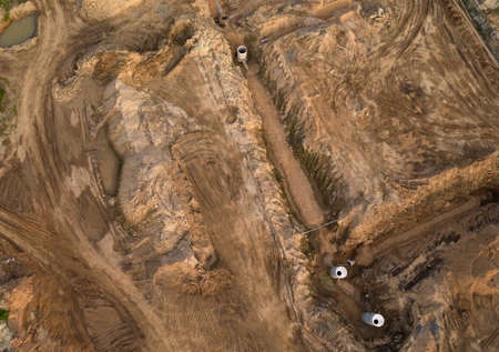 Laying of underground storm sewer pipes and sewerage wells. Installation of water main, sanitary sewer, storm drain systems. Ground water drainage pipes. Concrete pipe and concrete wells.の写真素材