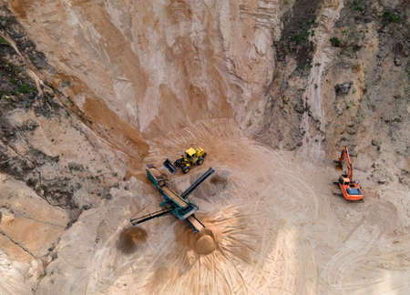 Arial view of the open pit mine. Front end loader loading gravel into stone jaw crusher in open-pit....