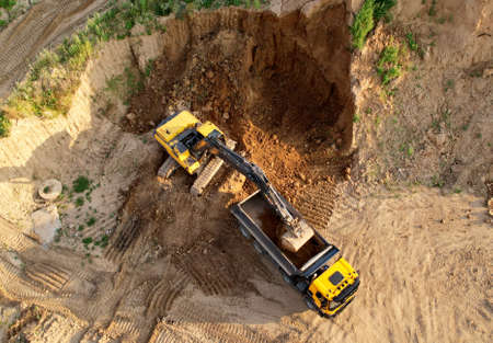 Excavator load the sand into dump truck. Aerial view of an backhoe on earthworks. Open pit...