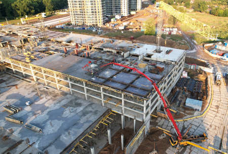 Pouring concrete from mixer truck. Tower crane on formwork at construction site. Reinforced...