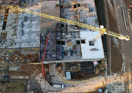 Pouring concrete from cement mixer. Tower crane on formwork at construction site. Reinforced...