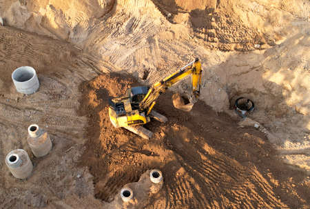 Excavator dig ground for sewerge construction. Trench for laying a concrete well ring and sewer...