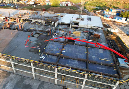 Pouring concrete from mixer truck. Tower crane on formwork at construction site. Reinforced...