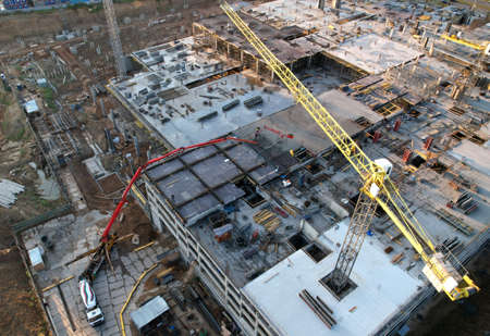 Pouring concrete from mixer truck. Tower crane on formwork at construction site. Reinforced...