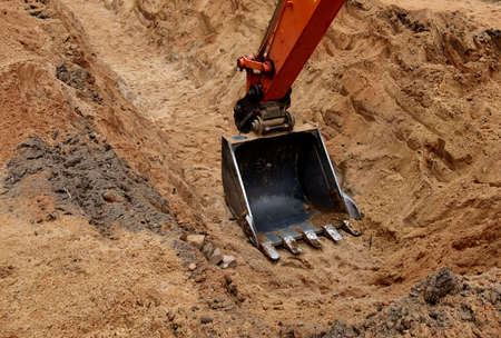 Excavator bucket for digging a pit and ditch at construction site. Large metal iron ladle for...