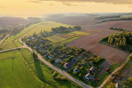Country houses in the countryside. Aerial view of roofs of green field with rural homes. Village with wooden home. Suburban house at farm. Housing outside the city. Agriculture, farming and agronomy.の写真素材