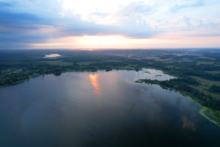 Lake among green trees in the countryside. Aerial view of a large lake or river against the backdrop of a sunset. Ecology and wetlands concept.の写真素材