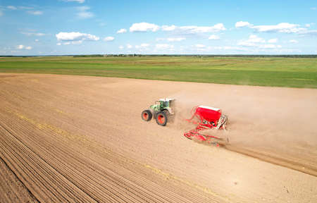 Tractor on sowing seed at field. Farming and seeding machine. Seeds sowing in farmers country....