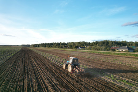Tractor on cultivating field work. Soil Tillage in farmers country. Agricultural tractor on cultivation field. Sowing seeds. Farming and seeding. Planting Equipment and Farm Machine.の写真素材