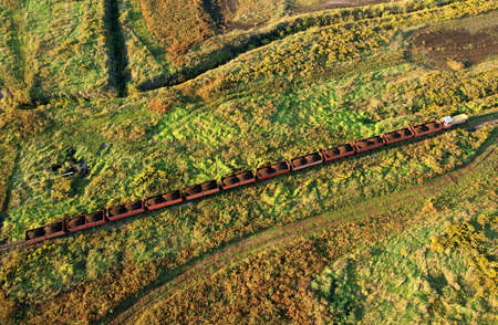 Train transports peat in freight wagons from peat extraction. Aerial view of the diesel locomotive on railroad in landscape at wetlands. Drone view of the peat bog railway at peatlands.の写真素材