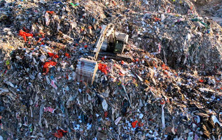Landfill with Construction and Demolition waste (CDW). Trash disposal for recycling and re-use. Excavator working on industrial landfill. Recycling of building waste materials. Secondary raw.の写真素材