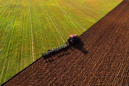 Tractor with Plow on Plowed. Plowing and Soil Tillage. Agricultural Tractor on Cultivation Field for...
