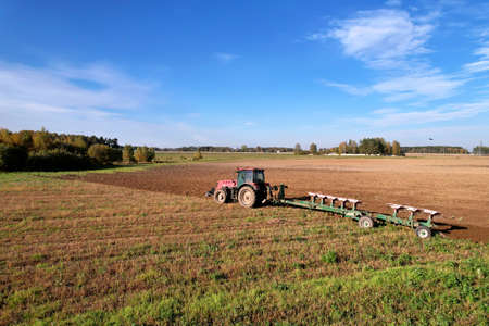 Tractor with Plow on Plowed. Plowing and Soil Tillage. Agricultural Tractor on Cultivation Field for...