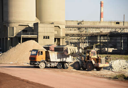 Cement plant site. Cement mix production process. Wheel loader loads chalk into dump truck at...