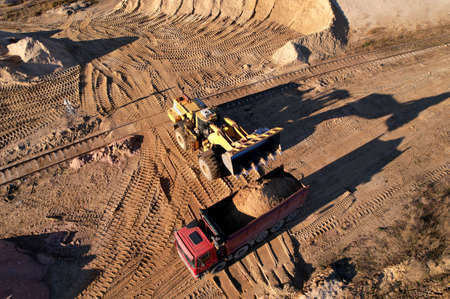 Wheel loader load the sand into dump truck in open pit. Developing the sand in the opencast. Heavy...