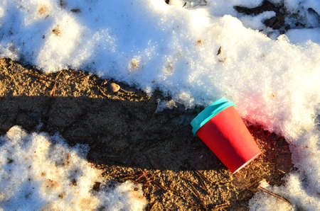 People throw coffee cup on snow. The problem of environmental pollution. Pile of abandoned garbage...