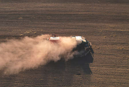 Agricultural tractor sowing seed onto at field. Farming and seeding concept. Seeds sowing in farmers...