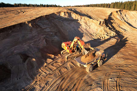 Mining excavator load the sand into dump truck in open pit. Developing the sand in the opencast....