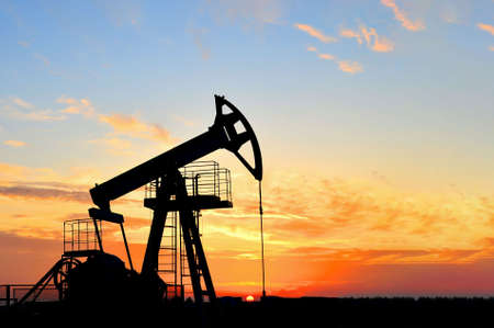 Crude oil pump jack at oilfield on sunset backround. Fossil crude output and fuels oil production. Oil drill rig and drilling derrick. Global crude oil Prices, energy, petroleum demandの写真素材