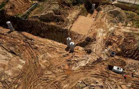 Laying of underground storm sewer pipes and sewerage wells. Installation of water main, sanitary sewer at conctruction site. Ground water drainage pipes. Concrete pipe and concrete wells.の写真素材