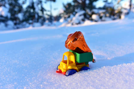 Toy truck with a Christmas ball on the background of white snow in the forest. oncept of preparing for the celebration of the New Year. Shopping gifts, decorating the Christmas tree and meeting Santa Clausの写真素材