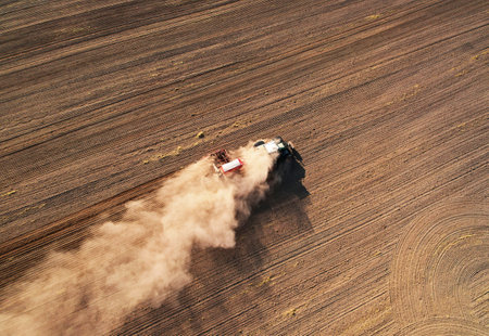 Tractor sowing seed on plowed field, drone view. Farming and seeding machinery for plowed field....