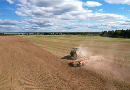 John Deere Tractor with disc cultivator Vaderstad Carrier 925 on cultivating field. Agricultural tractor on cultivation field. Soil Tillage and sowing seeds. Russia, Smolensk, September 07, 2021.のeditorial素材
