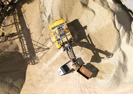 Mining excavator with electric shovel loading sand into haul truck in opencast. Belt conveyor and Sand Making Plant in open-pit. Sand crushing and bulk materials for the construction industry.の写真素材