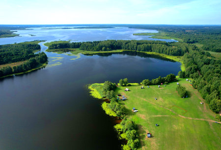 Lake in wild nature, aerial view. Lake on sunrise in summer. Aerial panoramic landscape view of lake in wildlife. Drone view of wetland in green colors. Rural environment, clean air and ecology. Pond.の写真素材