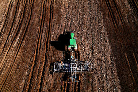 Tractor with cultivator plowing field. Tractor disk harrow on ploughing a soil. Planting in...