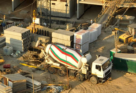 Pouring concrete in bucket from mixer truck. Tower crane on formwork at construction site. Reinforced concrete. Civil engineering during formworks. Concrete transport mixing truck during built.の写真素材