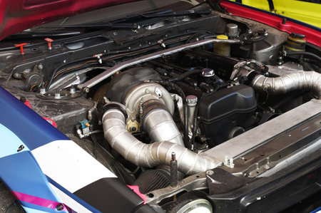 Sports car engine with turbine. An open race car hood on a pit stop while racing on a race track....
