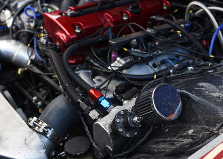 Sports car engine with turbine. An open race car hood on a pit stop while racing on a race track....