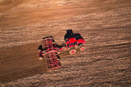 Tractor with cultivator plowing field. Tractor disk harrow on ploughing a soil. Planting in...