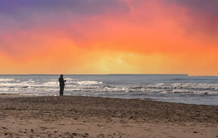 Fisherman is fishing on the seashore. Silhouette of a man with a fishing rod while fishing in the...