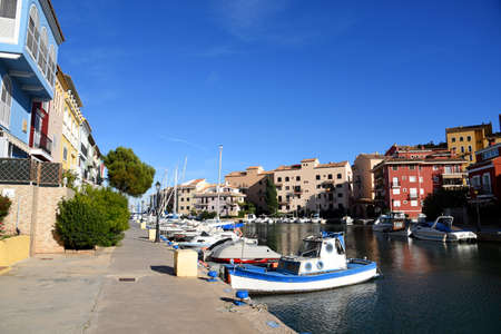 Yachts and motor boats in marina Port Saplaya, Valencia, Alboraya, Spain. Luxury yacht and fishing motorboat in yacht club on the background of the colorful houses at Mediterranean Sea. Sailing port.の写真素材