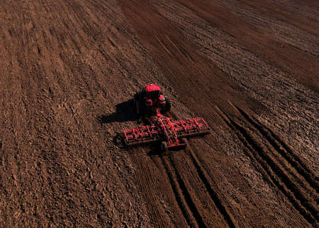 Tractor with cultivator plowing field. Tractor disk harrow on ploughing a soil. Planting in...