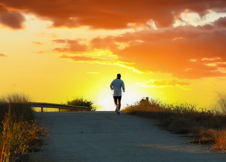Runner on sunset. Run in sprint on footpath. Man sprinter on sunset. Male running for exercise. Athlete runner feet running on sunrise. Person during Jogging at outdoors. Men on marathon of the running.の写真素材