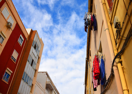 Clothes after washing are hanging to dry on the background of the facade of the house. Drying clothes outside after washing. Fresh shirt and clean jeans with shorts from the wash on street.の写真素材