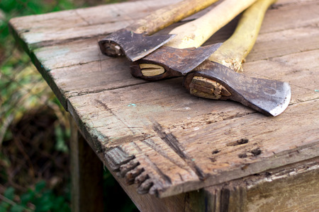 several axes lying on a wooden table in the countryside, in the summerの写真素材