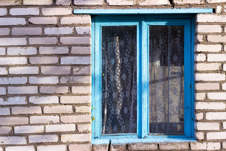 blue old wooden window in the house from a white brick villageの写真素材