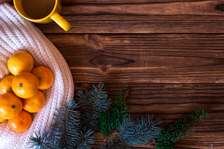 Christmas and New Year Mandarins next to the Christmas tree branches with cones on a wooden backgroundの写真素材