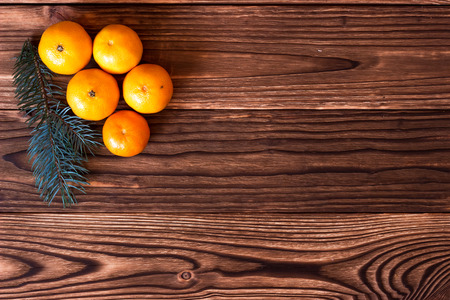 Christmas and New Year Mandarins next to the Christmas tree branches with cones on a wooden backgroundの写真素材
