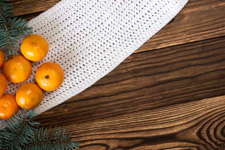 Christmas and New Year Mandarins next to the Christmas tree branches with cones on a wooden backgroundの写真素材