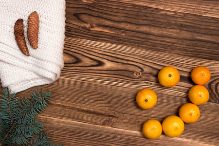 Christmas and New Year Mandarins in the form of a smile, next to the Christmas tree branches with cones on a wooden backgroundの写真素材