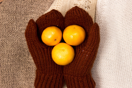 Christmas and New Year Mandarins crocheted, brown gloves on the background of colorful, warm sweatersの写真素材