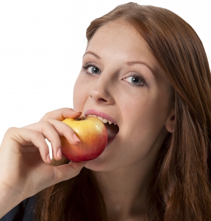 Young beautiful girl eating red apple isolated whiteの写真素材