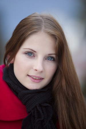happy gray-eyed girl in red coat and black scarfの写真素材