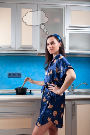 housewife with cloud of thoughts cooks food in modern kitchenの写真素材